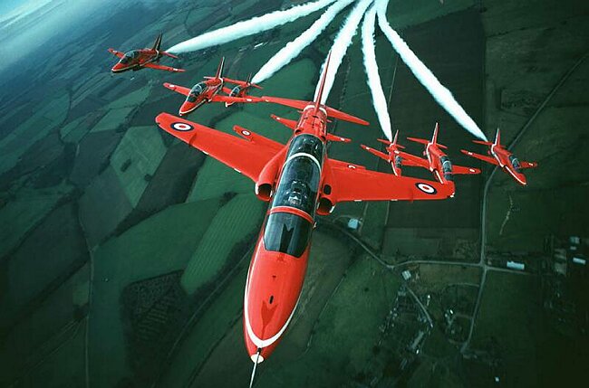 Red arrows in close formation over countryside.